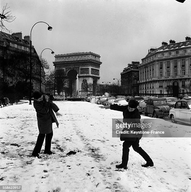 Jeunes parisiens faisant une bataille de boules de neige a deux pas de l'Arc de Triomphe a Paris, France, le 4 mars 1965.