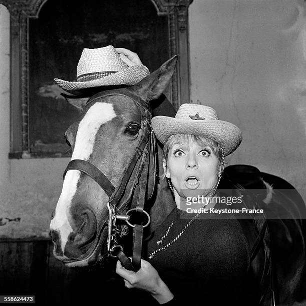 La chanteuse Annie Cordy baptise le chapeau texan a l'aide d'un cheval au manege de Neuilly le 17 mars 1965, en France.