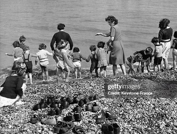 Petits vacanciers londoniens qui, découvrant la mer pour la première fois, mettent les pieds dans l'eau à Kingsdown, dans le Kent, au Royaume-Uni,...