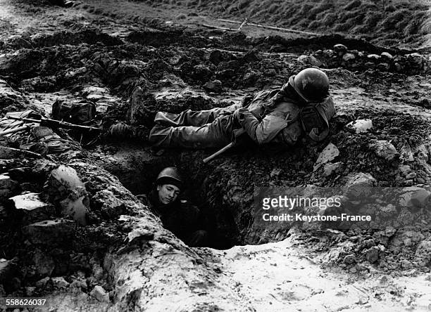 Après avoir marché toute la nuit et traversé le fleuve Roer, des GI se reposent dans une tranchée, en février 1945.