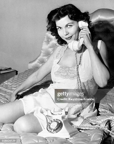 Femme assise sur son lit et téléphonant.