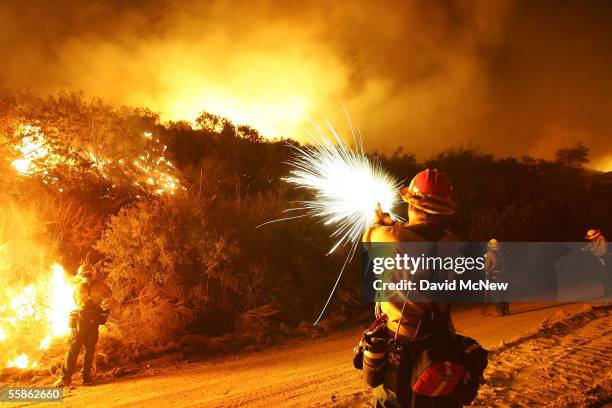 Forest Service firefighter uses a pistol to fire flares into brush to set a backfire to control the Woodhouse fire, also being called the Calimesa...