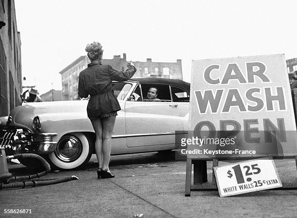 Jeune femme, habillée sexy, proposant à un homme de lui laver sa voiture, dans un garage de New York City, Etats-Unis.