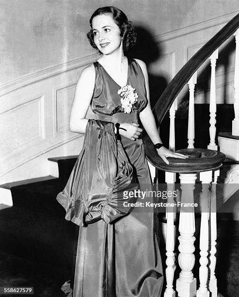 Olivia de Havilland portant un élégant ensemble du soir en taffetas composé d'une robe longue et d'un manteau, en 1936 à Hollywood, Californie.