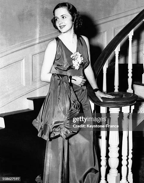 Olivia de Havilland portant un élégant ensemble du soir en taffetas composé d'une robe longue et d'un manteau, en 1936 à Hollywood, Californie.