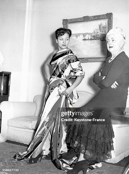 La grande créatrice de mode Nina Ricci, photographiée après avoir drapé sur une de ses mannequins un tissu soyeux, à Paris, France.