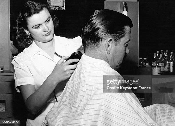 Cette jeune femme barbier est aussi une coiffeuse, en Allemagne le 23 mai 1957.