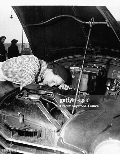 Joan Cooper, ancienne danseuse classique, travaille maintenant dans un garage et vérifie le niveau d'huile dans le moteur d'une voiture.