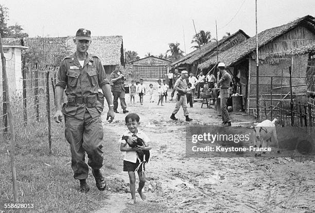 Des soldats americains se sont lies d'amitie avec les villageois de la region de Da Nang, un petit garcon s'est empare d'un coq pour accompagner un...