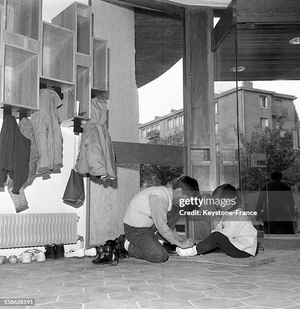 Enfants enlevant leurs chaussures avant d'aller écouter une lecture à la bibliothèque 'La joie par les livres', à Clamart, France, le 14 octobre 1965.