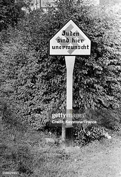 Exemple d'un panneau de signalisation en béton armé produit en masse sur lequel est écrit en allemand 'Les juifs ne sont pas désirés ici', circa 1940.