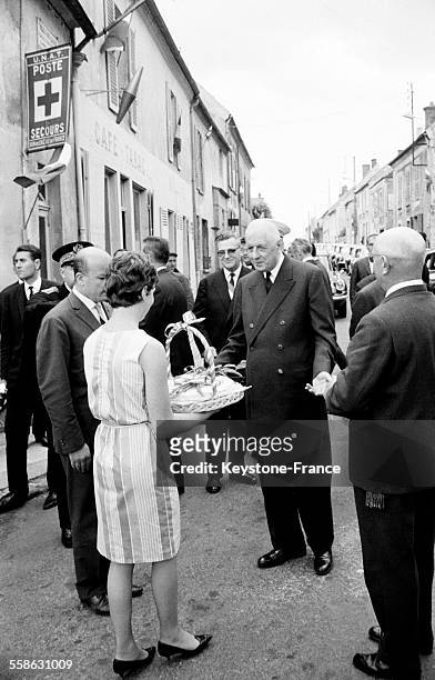 Une jeune femme offre une corbeille de fromages de Brie au Général de Gaulle le 17 juin 1965 à Chally-en-Brie, France.