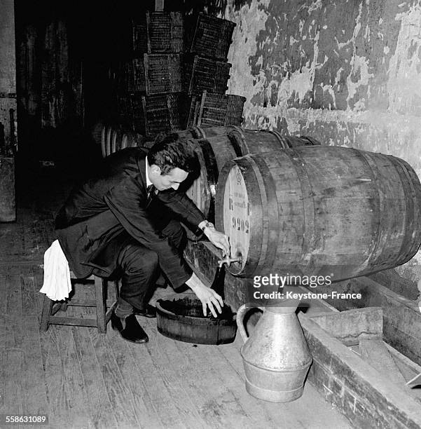 Un homme tire le vin d'un fût dans la cave du restaurant 'Drouant', circa 1960 à Paris, France.