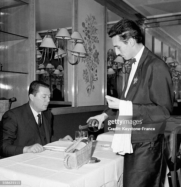 Un serveur du restaurant 'Drouant' verse du vin dans le verre d'un client, circa 1960 à Paris, France.