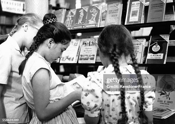 Petites filles en train de choisir leurs livres scolaires dans une grande librairie, à Paris, France, le 6 septembre 1960.