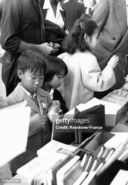 Enfants d'origine asiatique devant le rayon de fournitures scolaires d'une librairie, le 26 septembre 1956.