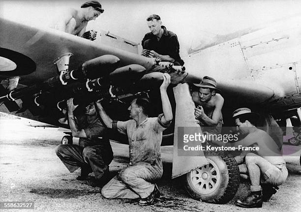Sur une base militaire japonaise, des soldats australien arment l'avion de chasse Mustang de la Royal Australian Air Force pour un raid sur la Corée,...