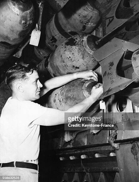 Soldat installant une bombe avec détonateur installée dans la soute d'un bombardier B-29 prêt à décoller d'un aéroport non identifié, le 17 juillet...