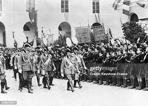 Accompagné d'officiers d'état-major, le roi d'Italie Victor-Emmanuel III passe en revue des balillas qui présentent les armes lors de la remise du...