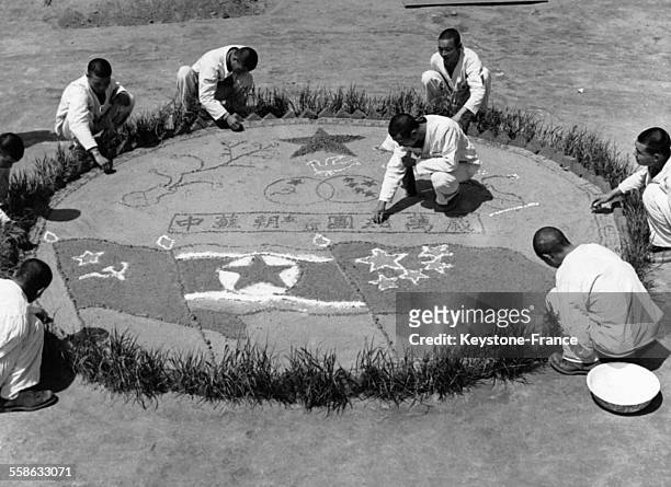 Paysans nord-coréens dessinant le drapeau nord-coréen et le drapeau soviétique sur le sol, en Corée du Nord circa 1950.
