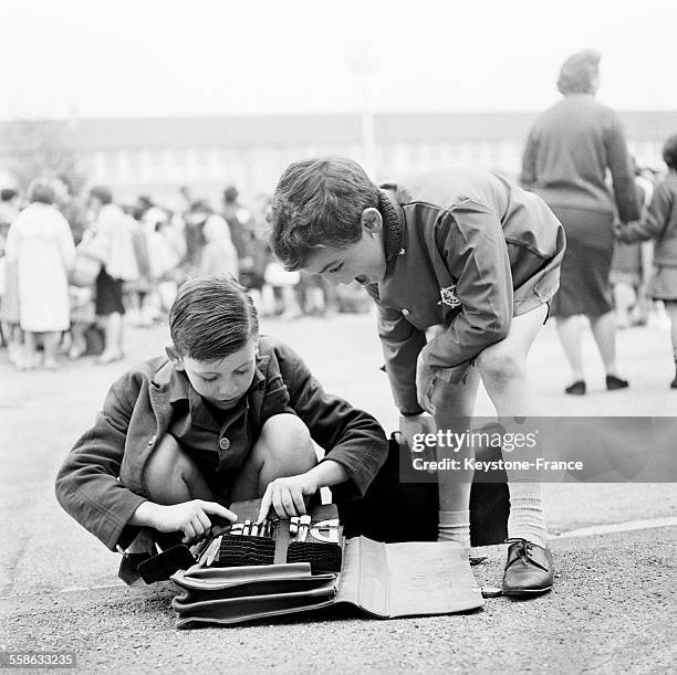 Rentree des classes pour les petits ecoliers qui, dans la cour de recreation, se montrent leurs nouvelles affaires scolaires, le 17 septembre 1965 en...