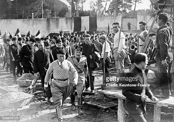 Mussolini, habillé en ouvrier, arrivant à l'emplacement où il va donner le coup de pioche symbolique pour les travaux de dégagement du mausolée...