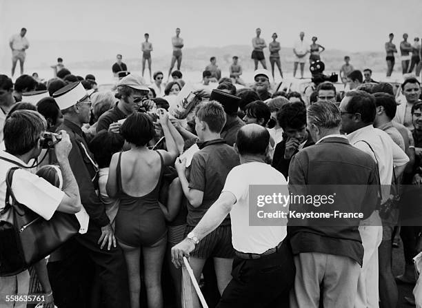 Johnny Hallyday signs autographs on the beach in Cannes, France, circa 1960.