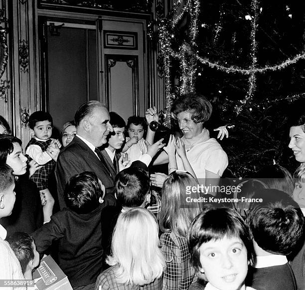 Au milieu de la joie générale, le Premier ministre Georges Pompidou et sa femme Claude distribuent les cadeaux accrochés à l'arbre de Noël aux...