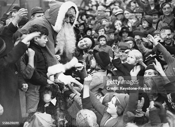 Distribution precoce de cadeaux par le Pere Noel a une foule d'enfants, chez Selfridges, a Londres, Royaume-Uni, le 31 octobre 1938.