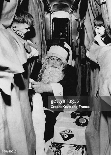 Pere Noel distribuant des cadeaux a des enfants dormant dans des lits couchettes d'un avion le soir du reveillon de Noel, a Chicago, Illinois.