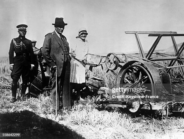 Mustafa Kemal Ataturk dans sa ferme à côté de sa tondeuse-liseuse avec en arrière-plan son garde du corps en Turquie le 23 juillet 1929.