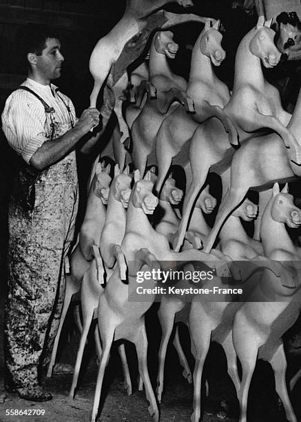 Ouvrier alignant des chevaux de bois dans une grande fabrique de jouet parisienne, un mois avant Noel, a Paris, France, le 26 novembre 1952.