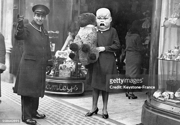 Femme deguisee avec une tete de poupon en train de faire ses achats de Noel, a Londres, Royaume-Uni, le 18 novembre 1929.