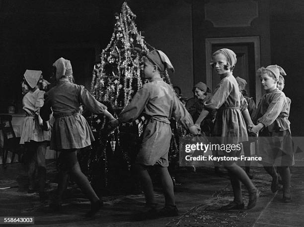 Enfants deguises en lutins faisant une ronde autour d'un sapin de noel pour celebre Noel a 'l'ancienne', a Copenhague, Danemark, le 3 decembre 1965.