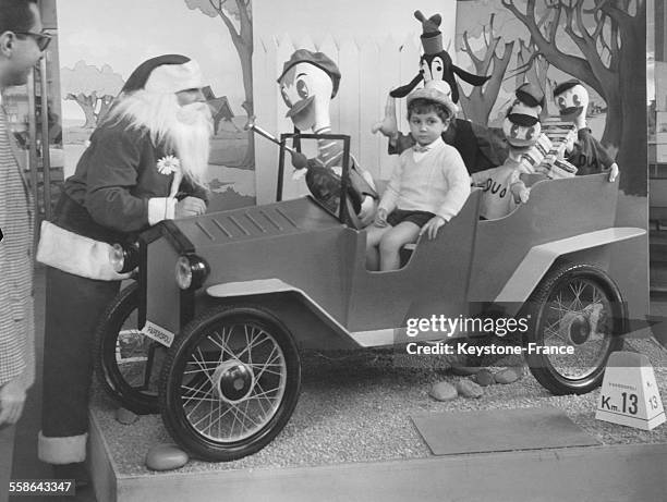 Enfant sur un stand photo avec le Pere Noel et la voiture de Donald Duck, a Rome, Italie, le 6 decembre 1961.