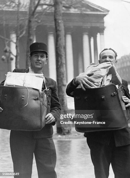 Deux facteurs avec des sacoches remplies de paquets et de cartes de voeux a l'occasion des fetes de fin d'annee, Place de la Madeleine, a Paris,...