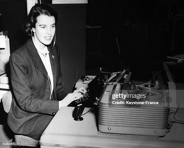 Une femme utilise le casque d'un stethoscope tout en tapant une lettre dictee par un magnetophone Grunding, au Salon de l'Equipement d'Usine, le 22...