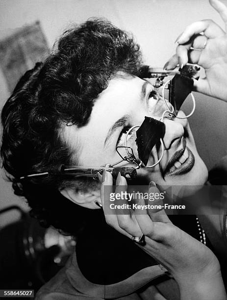 Jeune femme testant le verre sur des lunettes afin de verifier son opacite le 8 mai 1954 en Allemagne.