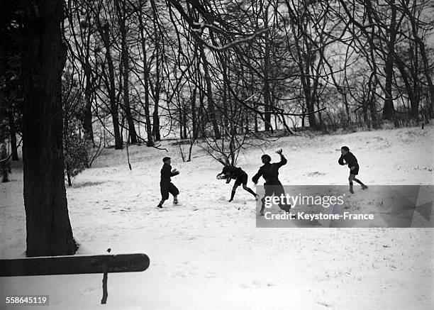 Enfants faisant une bataille de boules de neige dans un parc enneigé, à Vichy, France, circa 1940.