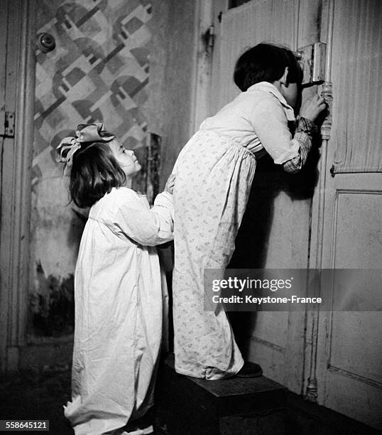Photo de propagande, ici, des enfants regardant par le trou de la serrure, à Vichy, France, circa 1940.