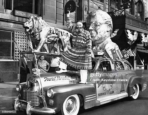 Pendant la Convention annuelle du Lions Club, défilé dans les rues de la ville de C W Bressler-Pettis, debout sur son étrange voiture or surmontée...