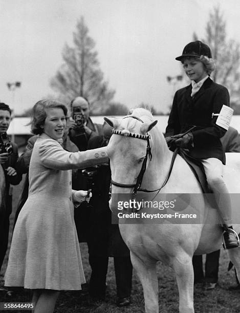 La Princesse Anne caresse le cheval Gathering Prosperity vainqueur du concours hippique du Royal Windsor Horse Show le 12 mai 1962 a Windsor,...