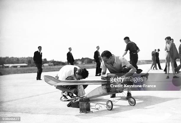 Deux hommes étudient un modèle réduit d'avion lors du meeting des modèles réduits, circa 1940.