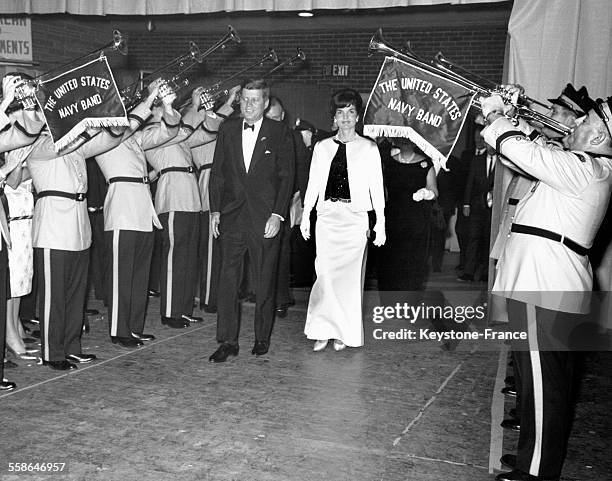 John Fitzgerald Kennedy et Jacqueline Kennedy arrivant à une soirée entourés par des musiciens de la Navy américaine aux Etats-Unis.