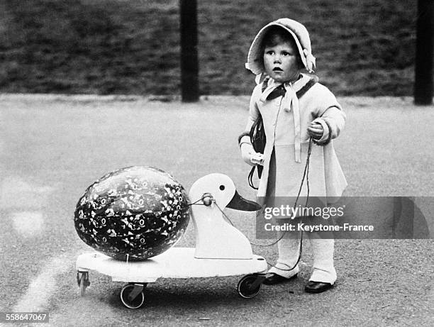 Ce malicieux bambin fait transporter le magnifique oeuf de Pâques dont on lui a fait cadeau par son canard en bois sur les Champs Elysées à Paris,...