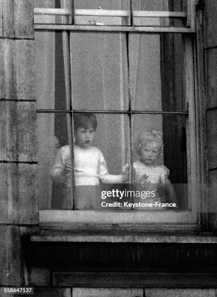 Prince Charles et Princesse Anne regarde a travers la fenetre du Palais de Buckingham, le 19 mai 1954 a Londres, Royaume-Uni.