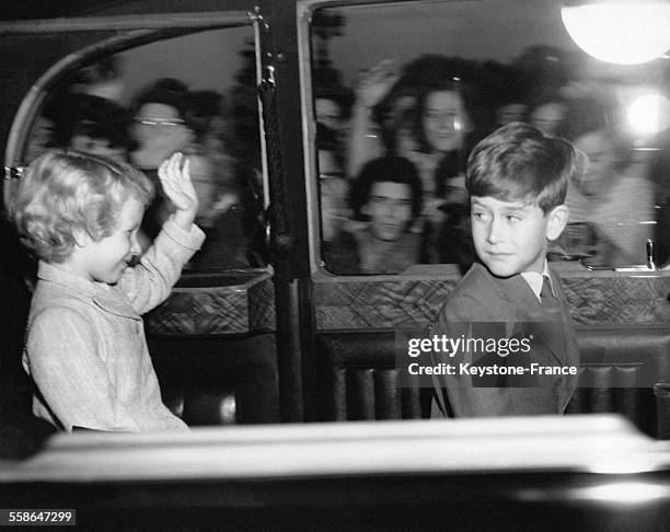 Prince Charles se retourne pour regarder la Princesse Anne saluant la foule alors qu'ils quittent le Palais de Buckingham en voiture, le 9 aout 1956...