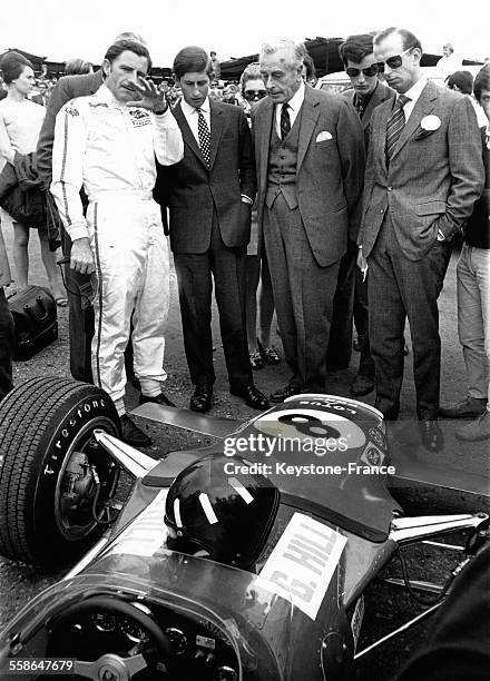 Graham Hill, coureur automobile, explique au Prince Charles, au Comte de Mountbatten et au Duc de Kent, la particularite de sa Formule 1 sur le...