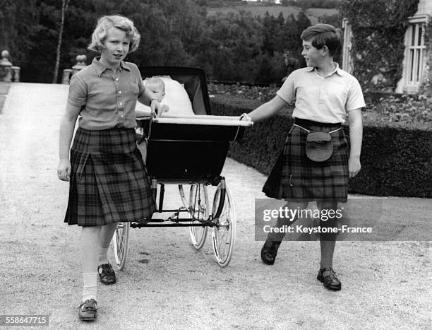 Le Prince Charles et la Princesse Anne poussant le landau du Prince Andrew dans le jardin du Chateau de Balmoral durant leurs vacances d'ete, circa...