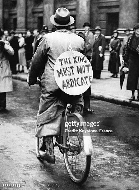 Homme a bicyclette avec une pancarte sur le dos contre l'abdication du roi Edward VIII, le 5 decembre 1936, a Londres, Royaume-Uni.